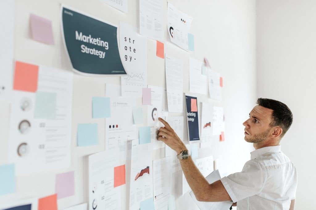 Marketing strategist analyzing conversion optimization data on whiteboard with charts and sticky notes for lead generation planning